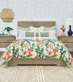 A bed dressed in a tropical floral comforter and matching pillows, styled in a bedroom with wood nightstands, a patterned wallpaper background, a hanging lamp, and a rug.