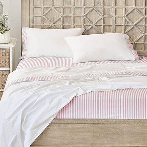 A bed with bottom and top sheet set and pillows. White pillows and top sheet feature pink and white vertically striped trim and a matching pink/white striped bottom sheet, set against a light wood geometric headboard and foot board.